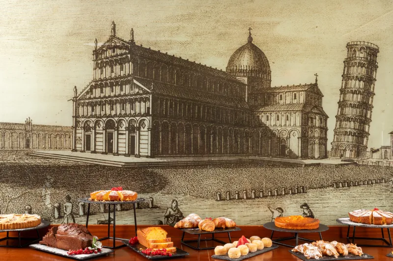 Buffet con pasticceria assortita e croissant freschi davanti a illustrazione storica di Pisa - Hotel La Pace, BZAR hotels a Pisa